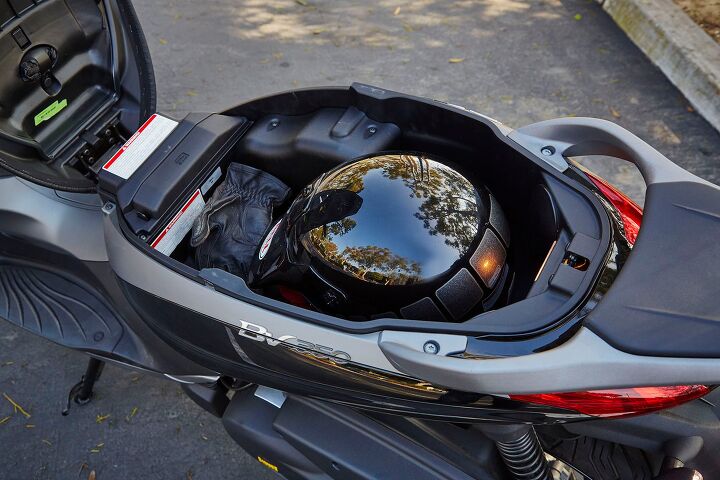 A front-hinging seat makes the storage compartment readily accessible. There’s only room for one helmet, but note the little pouch underneath the seat itself (above the green sticker). That’s a waterproof cover for the seat, another nice detail that helps separate the BV350 from the rest.