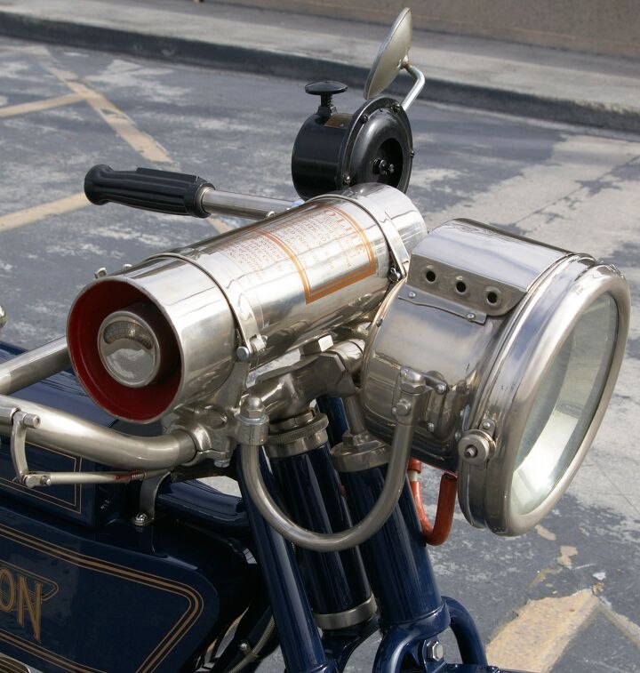 Works of techno-art in their own right, the Henderson’s acetylene-powered headlamp and canister that contains its fuel, a mixture of calcium carbide and water. First discovered in 1892, acetylene soon powered lighting for lighthouses, miner’s caps, bicycles and cars. Seen here also mounted on the handlebar is a large horn sometimes mistaken for a siren. Just press down on the plunger to get tooting.