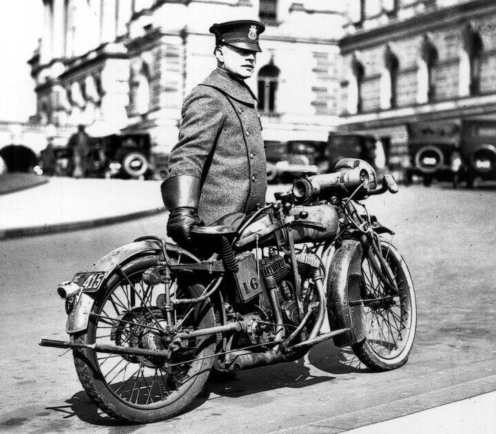 What appears to be a 1918 Indian Powerplus serves as a member of the Washington, D.C. police department and stands at the ready along with its gauntlet-wearing officer. The photo was snapped in 1924. With electric lighting, leaf spring front suspension, klaxon horn, this Indian was loaded for bear. The small toothed gear attached to the rear fender stay activates the siren mounted to the top of the gas tank.