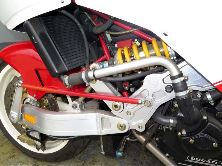 The Tesi theme was to separate suspension from steering. That red rod allows adjusting the angle of the kingpin inside the hub, what would be rake and trail on a conventional bike.