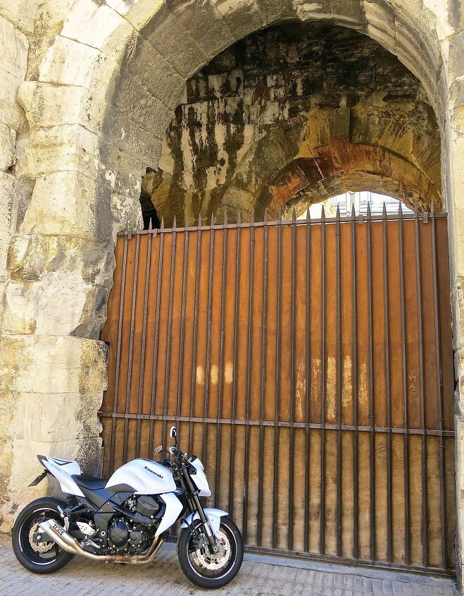 New and old. The sporty Kawasaki stands in contrast with the Roman coliseum in Arles, now an active bullfighting stadium.